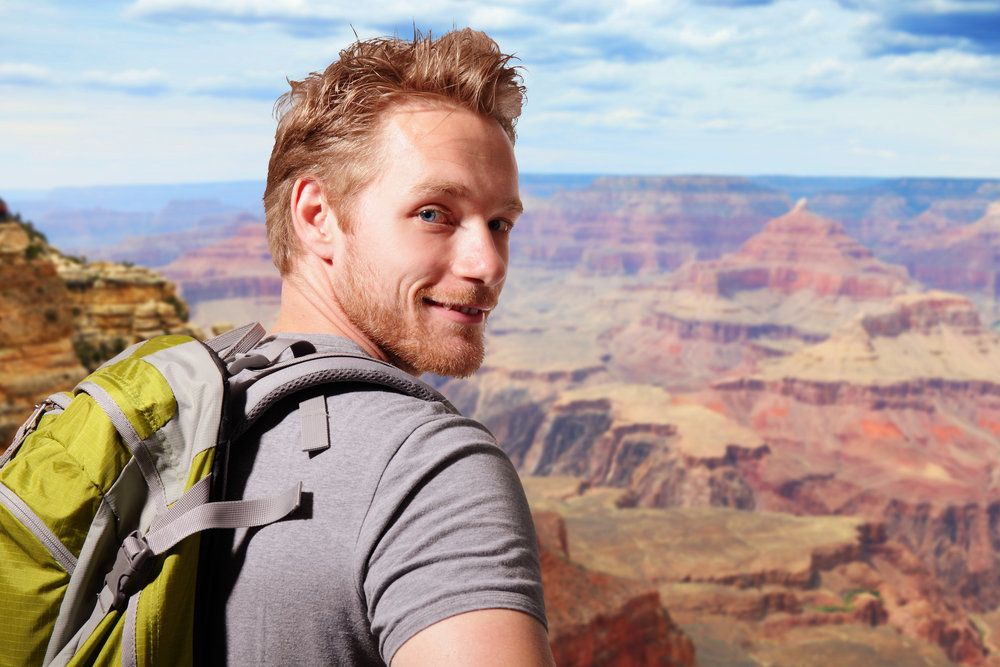 Young man hiking grand canyon looking back over shoulder